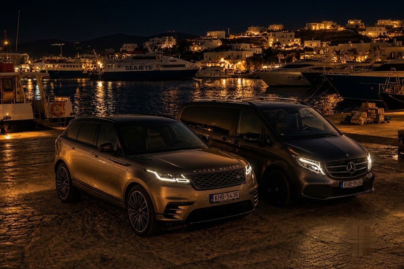 Range Rover Velar and Mercedes V-Class of Paros Elite Transfers parked at Paros port at night, SEAJETS ferry and town lights glowing behind